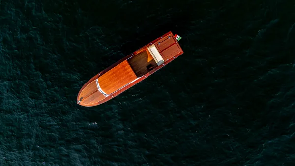 Vista dall'alto della barca in legno che scivola sulle acque scure del Lago di Como