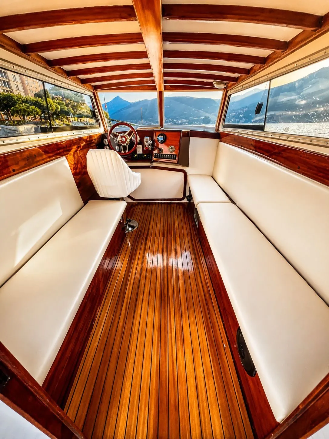 Dentro la cabina chiusa: panche color avorio, pavimento e soffitto in legno lucido e posto di guida con vista su lago e montagne